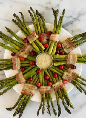 Fun and festive paleo & Whole30 dish with only a few ingredients, a Bacon Wrapped Asparagus Wreath make the perfect appetizer or side at holiday gatherings! - Eat the Gains