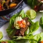 Lettuce cup filled with steak fajitas topped with avocado and pico de gallo