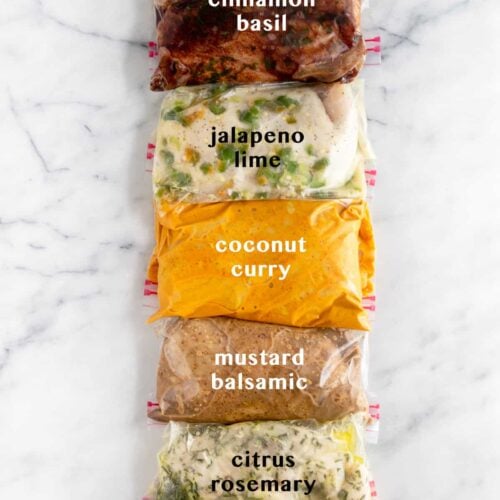 5 plastic bags on white counter top filled with Whole30 Chicken Marinade 5 different ways. Text overlay of what each marinade is - cinnamon basil, jalapeño lime, coconut curry, mustard balsamic, citrus rosemary.
