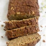 Three slices of Paleo Zucchini Banana Bread cut off from the loaf falling over with the loaf and a banana behind it