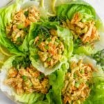 Large large filled with lettuce cups filled with Paleo Buffalo Ranch Chicken Salad with green onion and lemon wedges as garnish