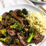 White plate filled with paleo beef & broccoli and cauliflower rice, topped with sesame seeds