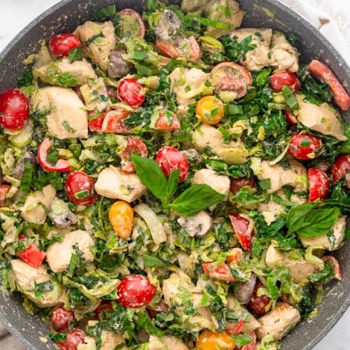 A pan filled with creamy balsamic chicken and veggies made in one pan and done in 30 minutes. It is topped with fresh basil and a small bowl of basil is next to it.
