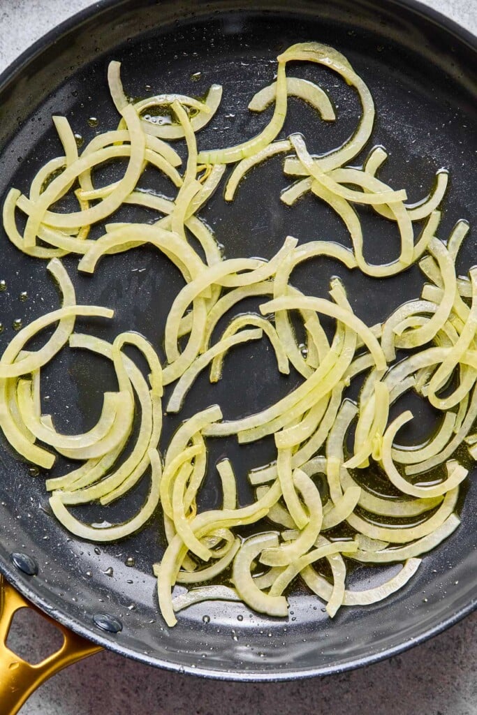Large skillet with saut&eacute;ed sliced onions in it.