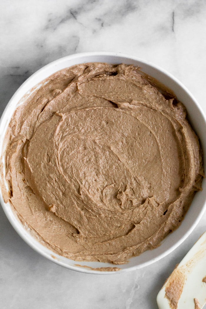 Coppa bianca riempita con yogurt al burro di arachidi al cioccolato.