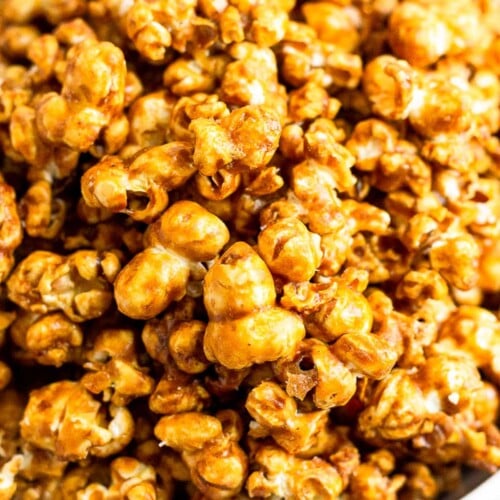 A close up shot of homemade caramel popcorn in a white bowl.
