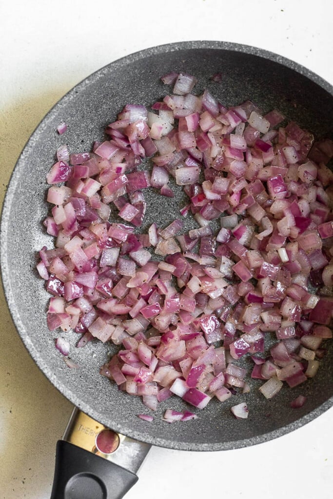 Small skillet filled with saut&eacute;ed diced red onions.