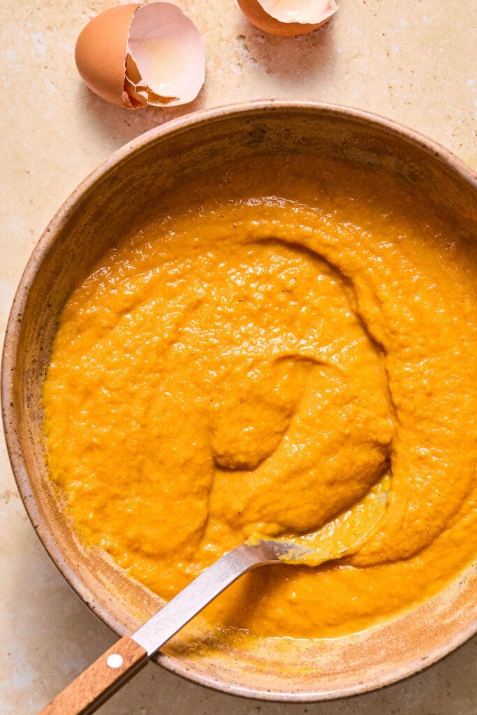 A large mixing bowl filled with a wet batter with a spoon in it.