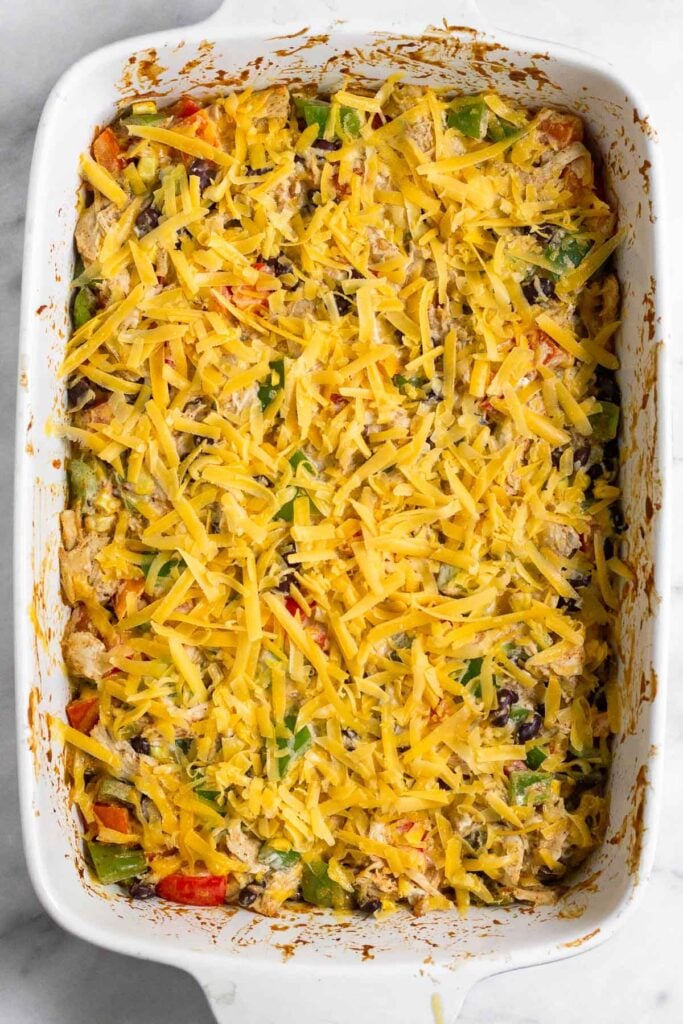 Chicken casserole topped with shredded cheese before it is baked.