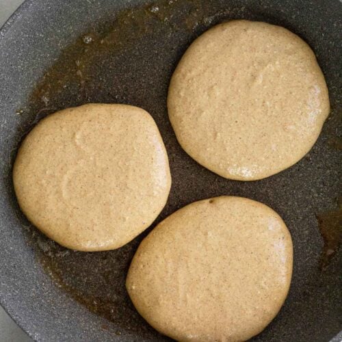 Skillet with 3 pancakes on it before they are flipped.