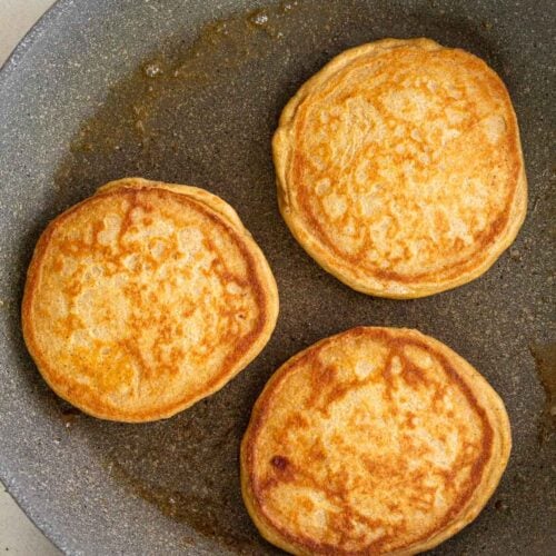 Three pancakes on a grey skillet.