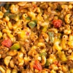 Close up of cheesy taco pasta with ground beef and veggies in a skillet.