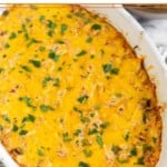 Hot chicken dip topped with melted cheese and cilantro in a white baking dish.