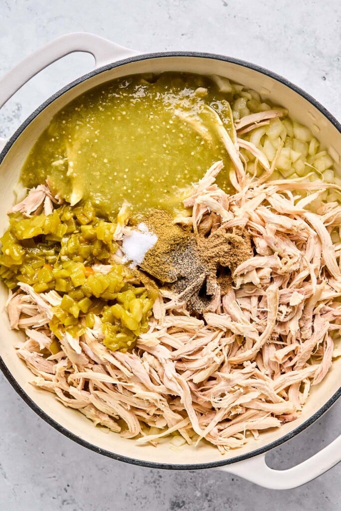 Large enameled pan with saut&eacute;ed onions, shredded chicken, diced green chiles, green salsa, and spices.