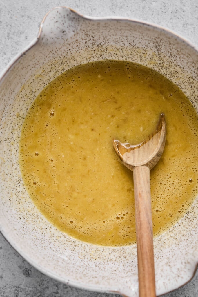 A mixing bowl with a wet batter and a wooden spoon in it.