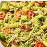 Chicken bacon ranch pasta salad in a large white bowl. There is a spoon in the bowl and it pasta salad is garnished with dill.