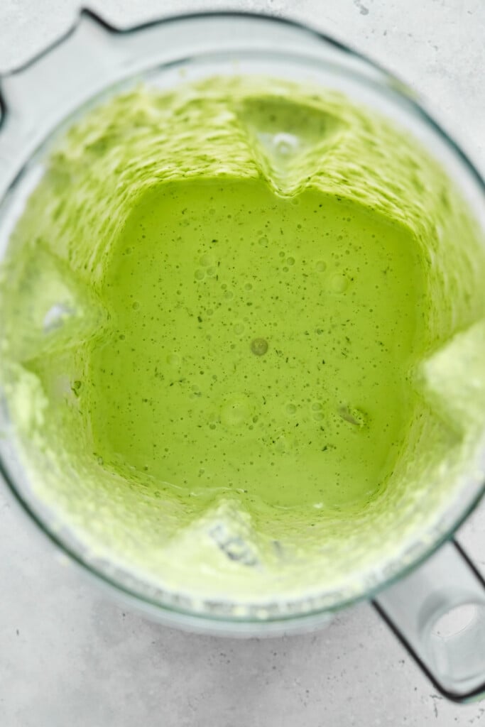 Overhead shot of a creamy green sauce in a blender.