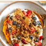 Sweet potato breakfast bowl with greek yogurt, berries, nut butter, granola, and topped with cinnamon.