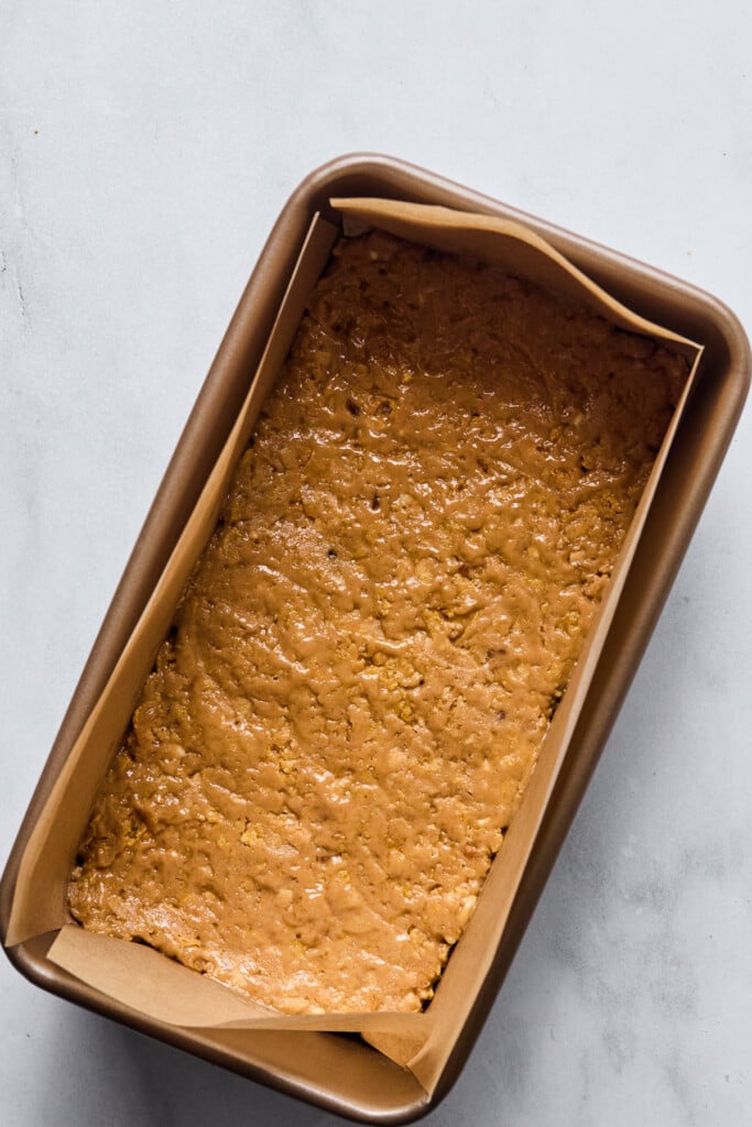 Crunchy peanut butter dough pressed into a bread pan lined with parchment paper.