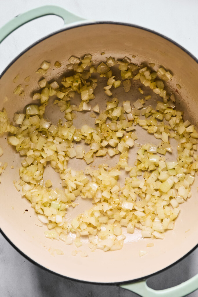 Overhead shot of a large Dutch oven filled with saut&eacute;ed onions and garlic.