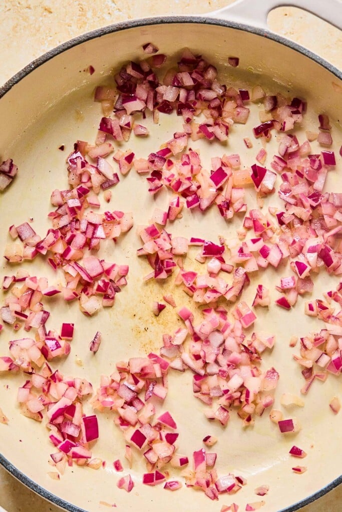 Large enameled pan filled with saut&eacute;ed red onions.