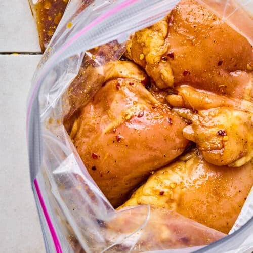 Chicken thighs marinating in a plastic bag.