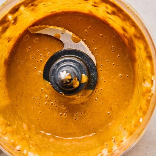 Small food processor with a creamy almond butter sauce in it.