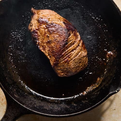Steak cooking in a cast iron skillet.