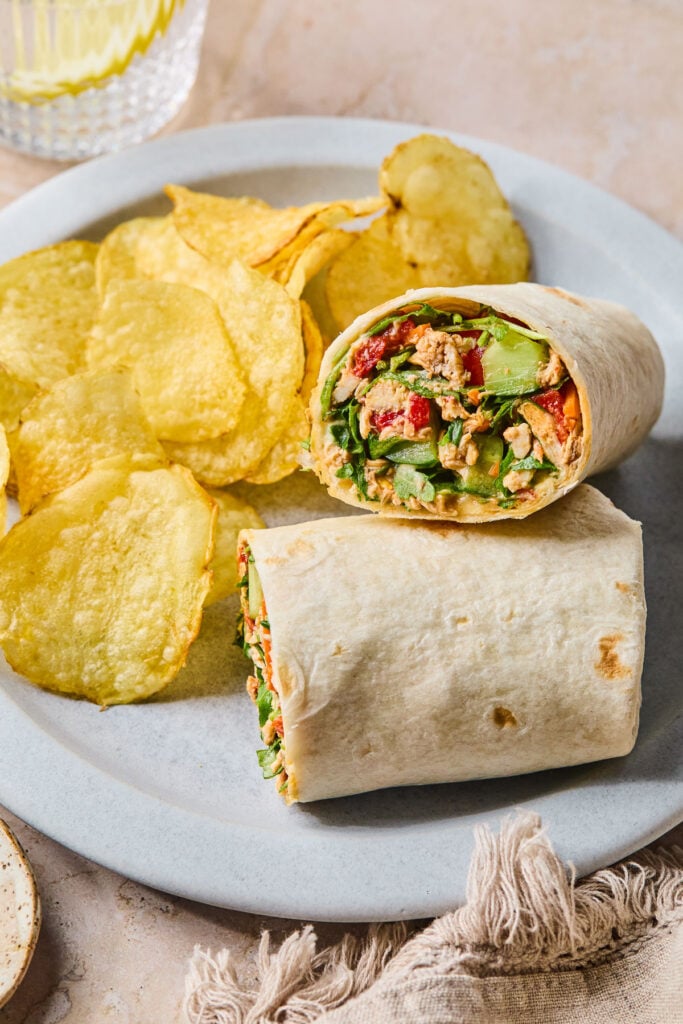 Chopped salad wrap with chicken and veggies on a plate with potato chips.