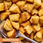 Sourdough croutons in a bowl with a metal spoon.