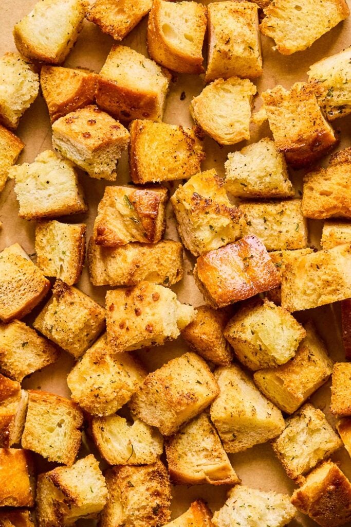 Overhead shot of a bunch of homemade sourdough croutons on a baking sheet.