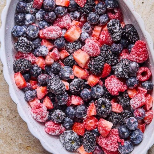 A small oval casserole dish of filled with mixed berries that have been lightly tossed in flour.