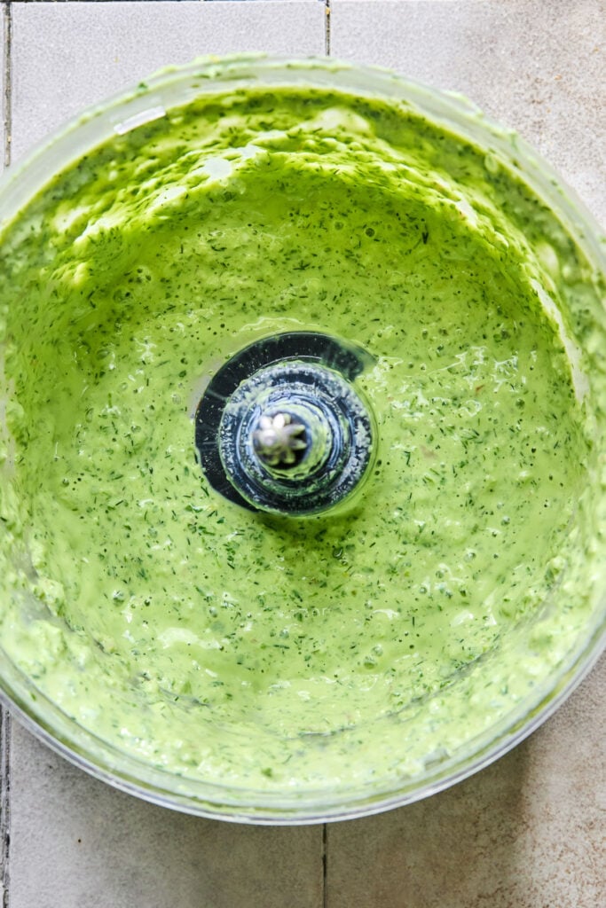 Homemade green goddess dressing in a food processor bowl.