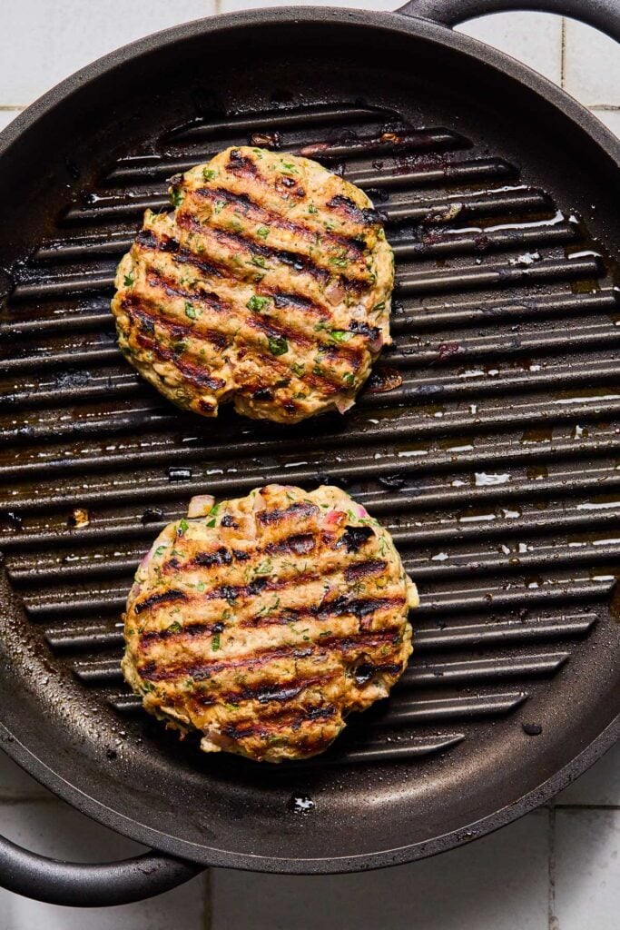 Turkey burgers cooking on a grill pan.