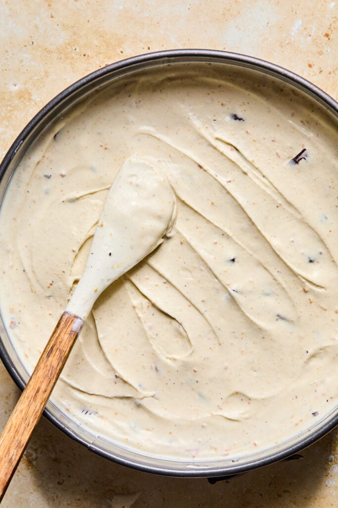 A cake pan filled with a mixture of vanilla ice mixed with peanut butter and peanut butter cups. A spatula is resting on top of the ice cream mixture.