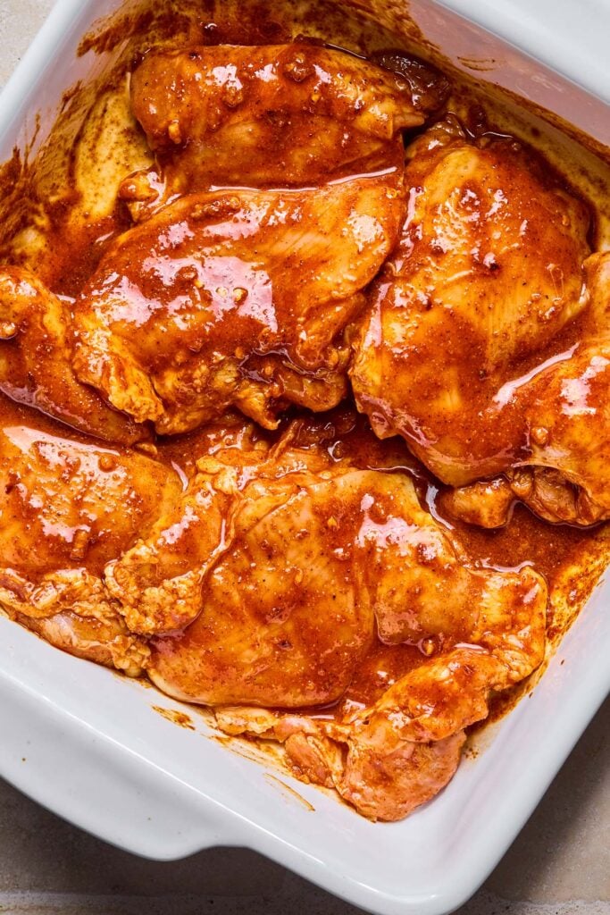 A casserole dish with marinated chicken thighs in it.