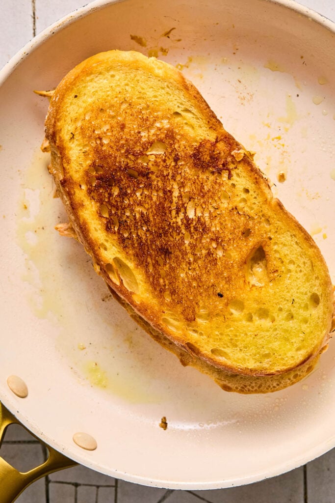 Buffalo grilled cheese cooking in a skillet.