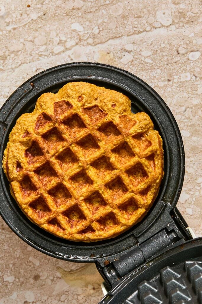 Mini waffle maker with a cooked waffle in it.