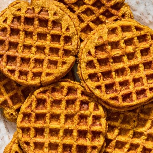 A plate with a bunch of pumpkin waffles spread on it.