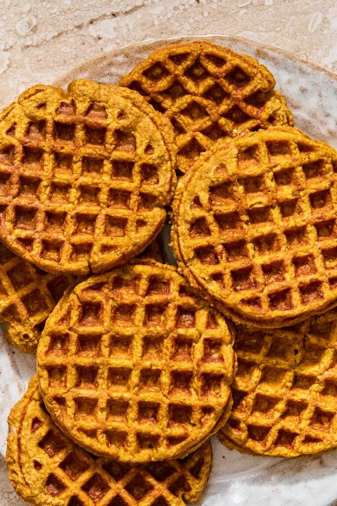 A plate with a bunch of pumpkin waffles spread on it.