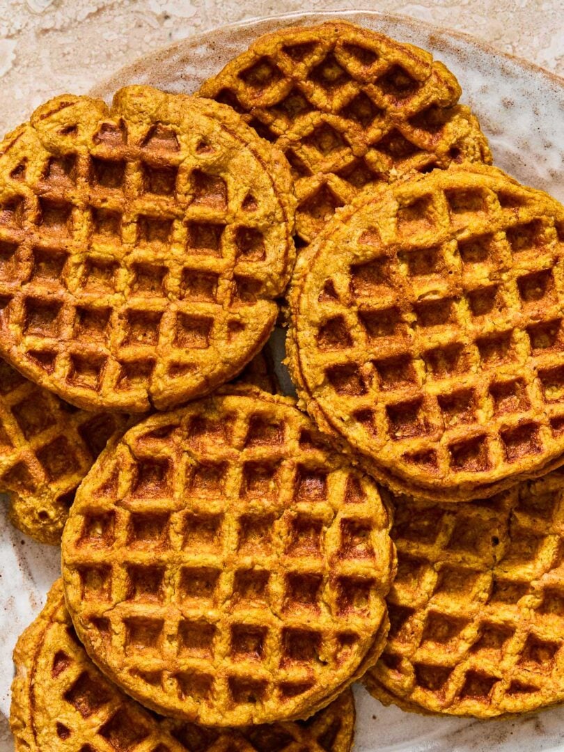 A plate with a bunch of pumpkin waffles spread on it.