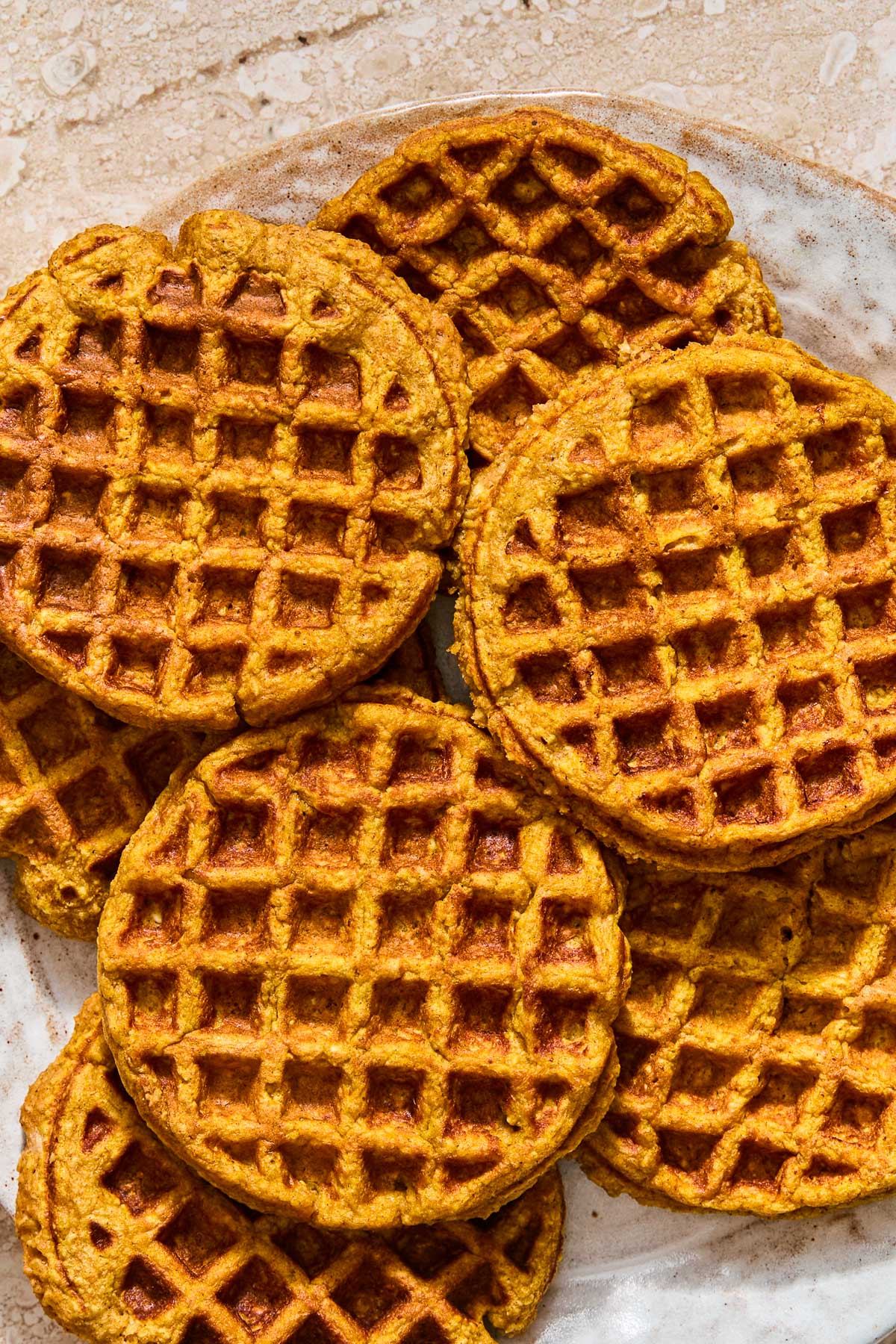 A plate with a bunch of pumpkin waffles spread on it.
