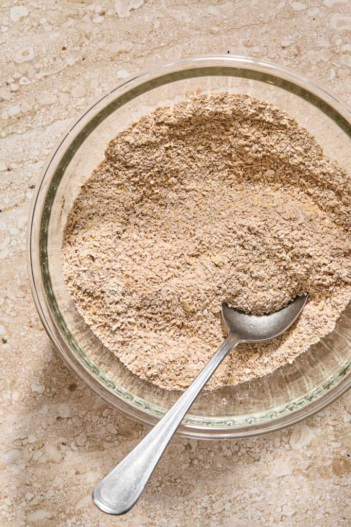 An overhead shot of a bowl with flour and spices mixed. A spoon is also in it.